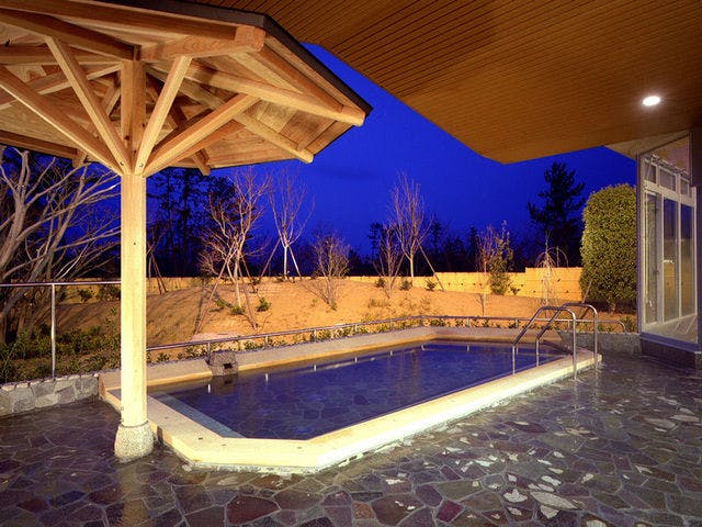 บ่อน้ำพุร้อนกลางแจ้งในบรรยากาศยามค่ำคืน.