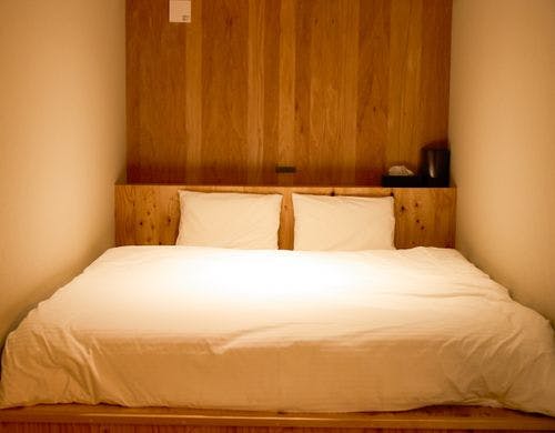 天然木に囲まれたダブルベッド。