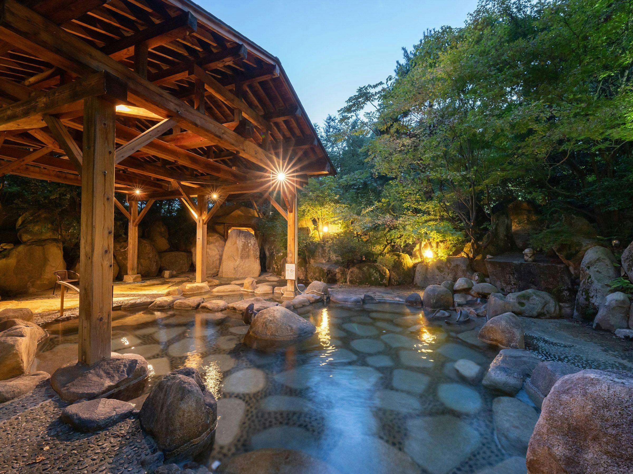 บ่อน้ำพุร้อนกลางแจ้งที่มีแสงไฟในยามค่ำคืน