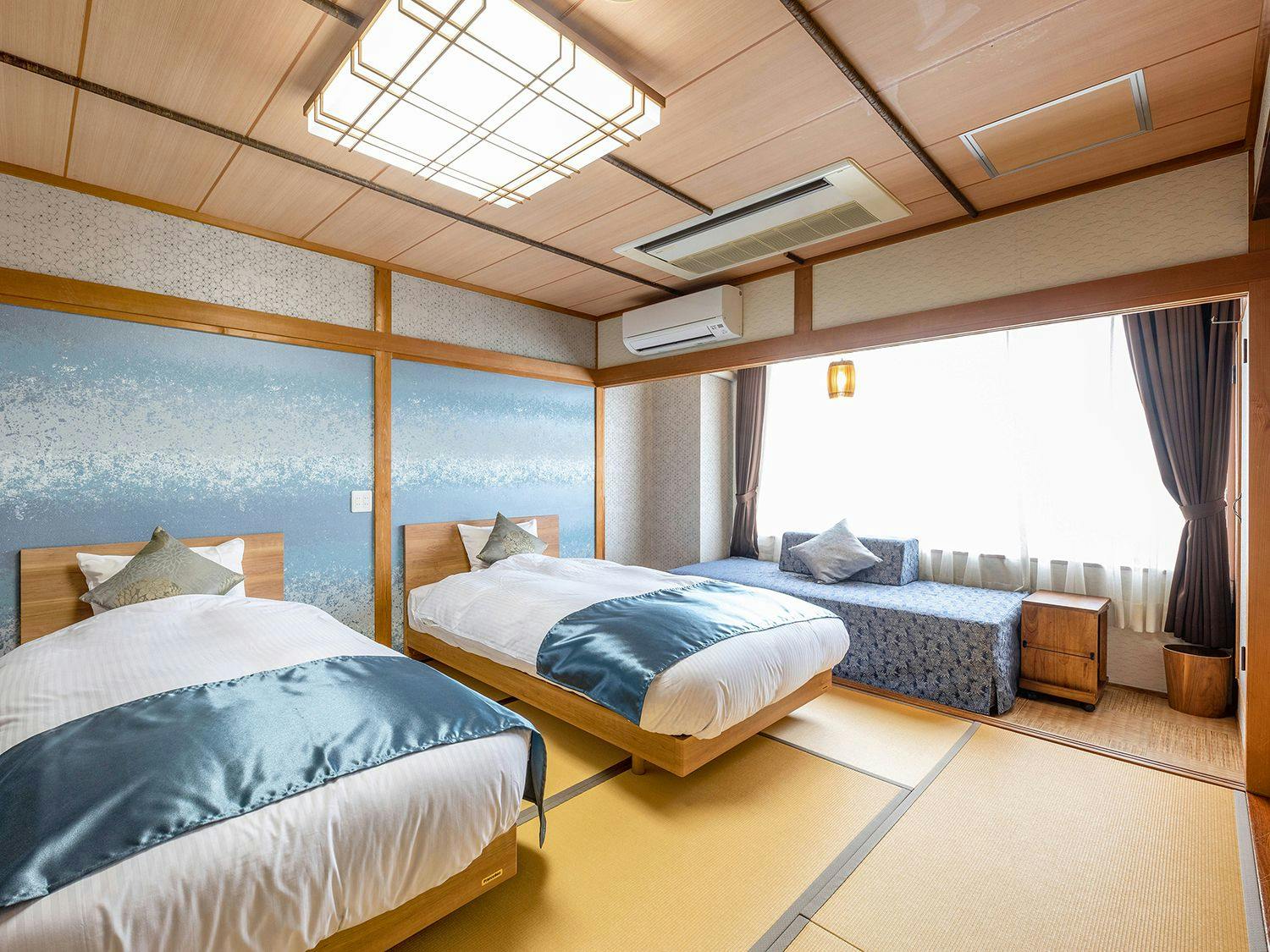 Kamar bergaya Jepang dengan 2 tempat tidur dan 1 sofa bed.