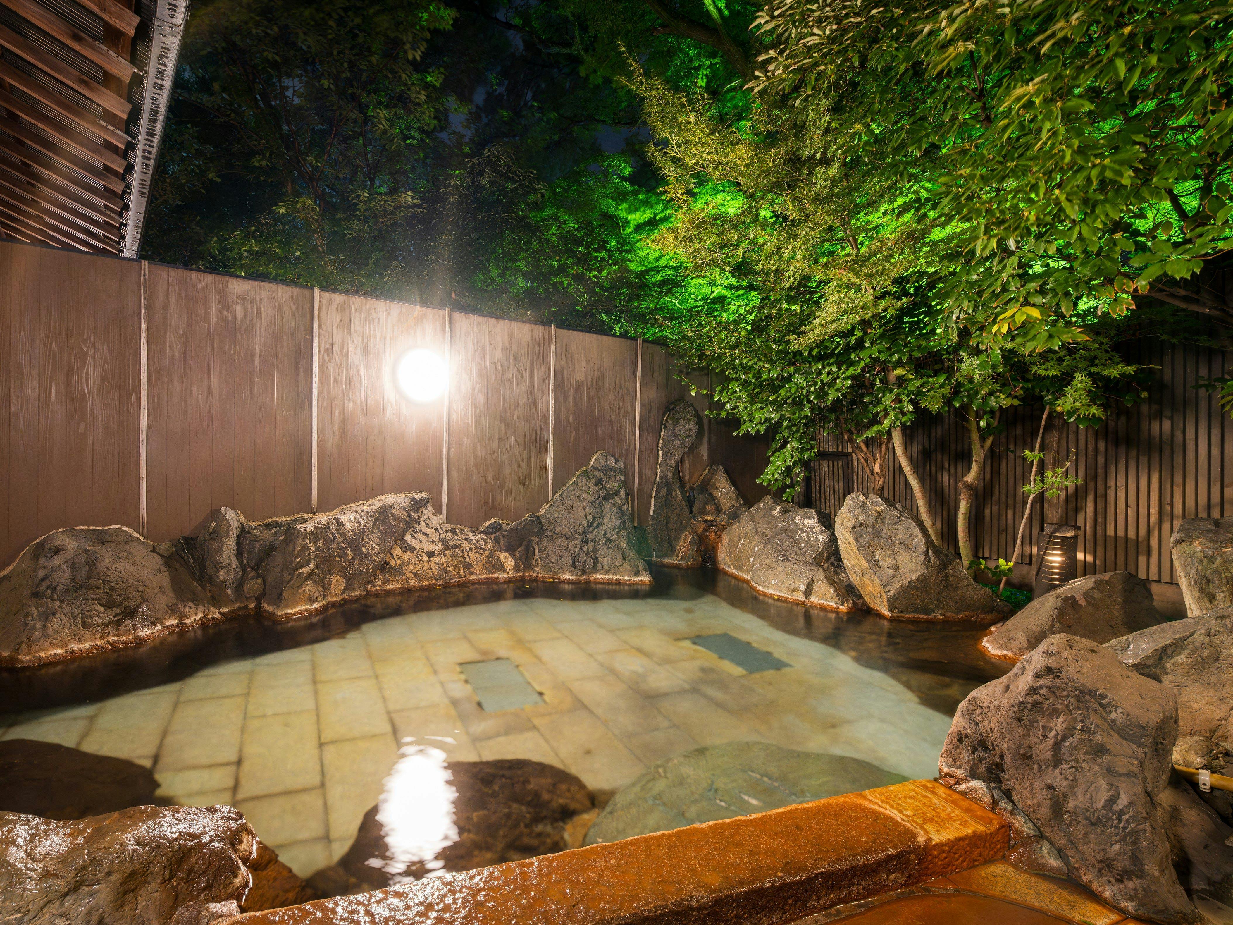 ออนเซ็นกลางแจ้งยามค่ำคืนที่มีแสงไฟประดับ